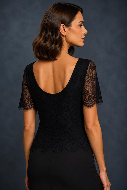 A woman shown from the back wearing a black lace short-sleeve dress against a dark textured studio background.