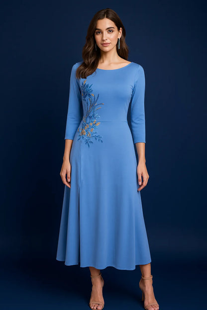 Woman wearing a blue tango dress with floral embroidery on a dark background