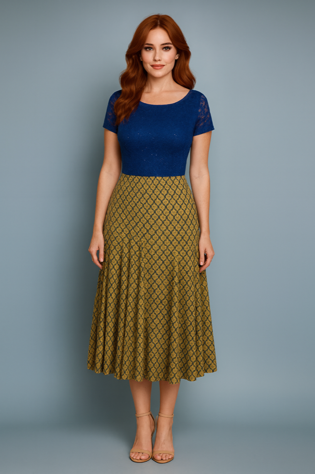 Woman wearing a blue tango top and green patterned tango skirt against a gray background