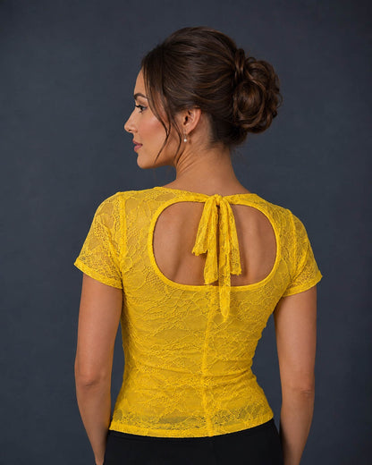 A woman shown from the back wearing a bright yellow lace short-sleeve top with a large open back and tie detail.