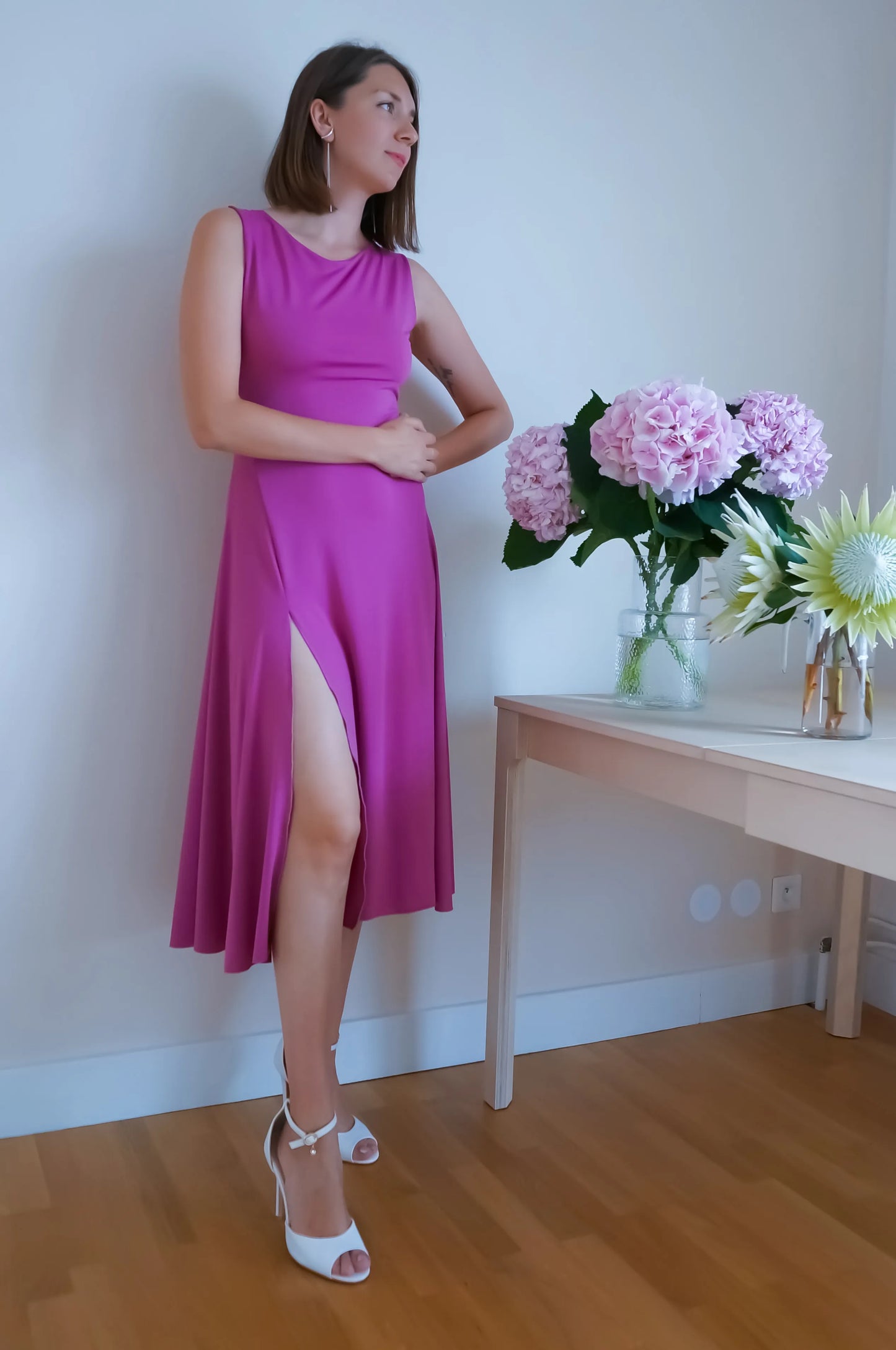 Woman in a pink tango dress standing next to a table with flowers