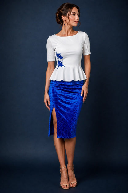 Woman wearing a white silky jersey tango top with blue embroidered fish appliqués and peplum waist, paired with a blue velvet tango skirt.