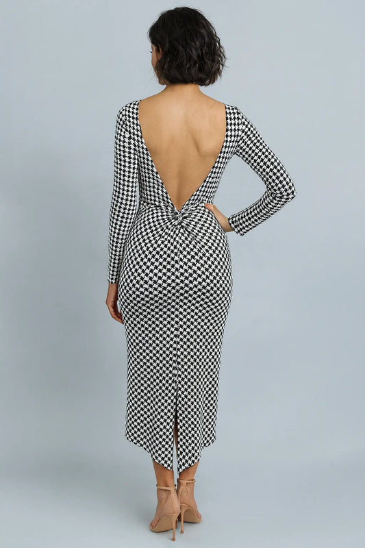 Woman wearing a black and white checkered tango dress with an open back on a gray background