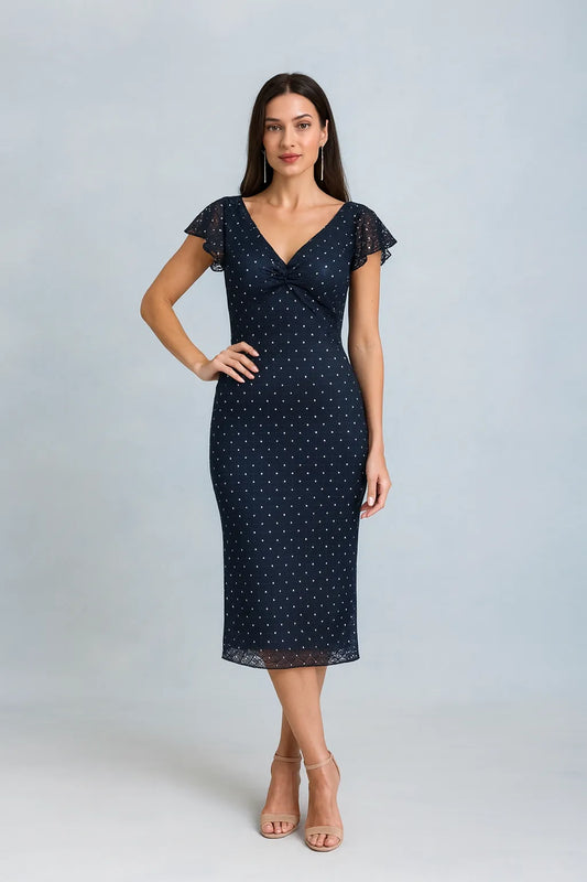 Woman wearing a navy tango dress with white polka dots on a light gray background