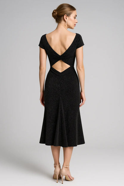 Black tango dress with open back worn by a model on a gray background