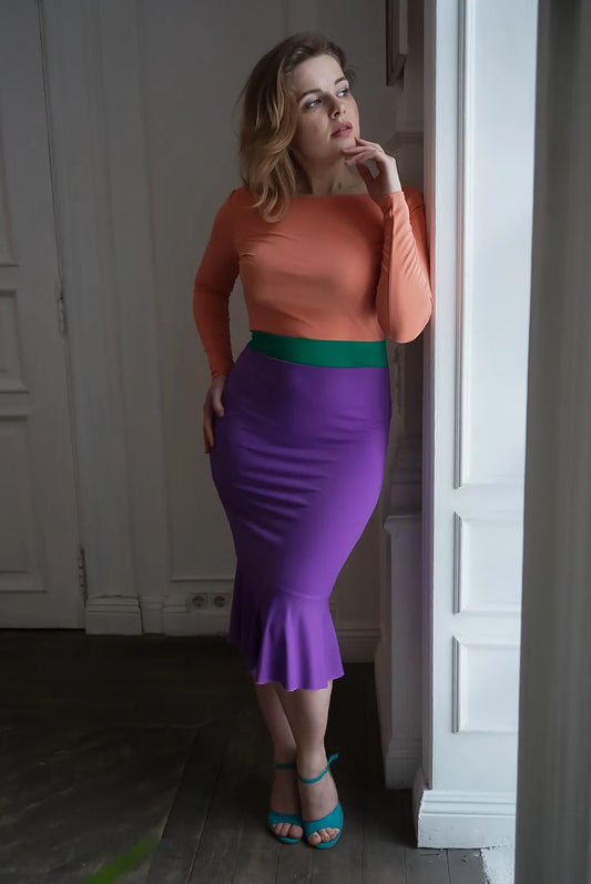 Woman wearing a peach and purple tango dress standing in a doorway.