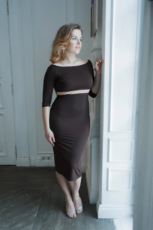 Woman wearing a brown tango dress standing in a room with white paneled walls.