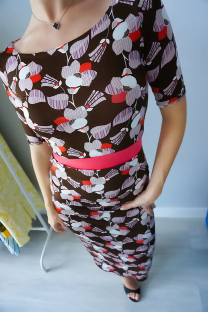 Woman wearing a patterned tango dress with a pink belt against a plain background