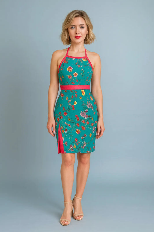 Woman wearing a teal floral tango dress with red accents on a gray background