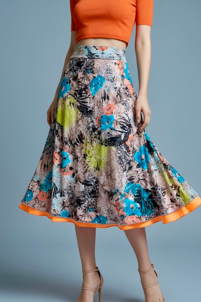 Woman wearing an orange top and a colorful floral tango skirt on a gray background