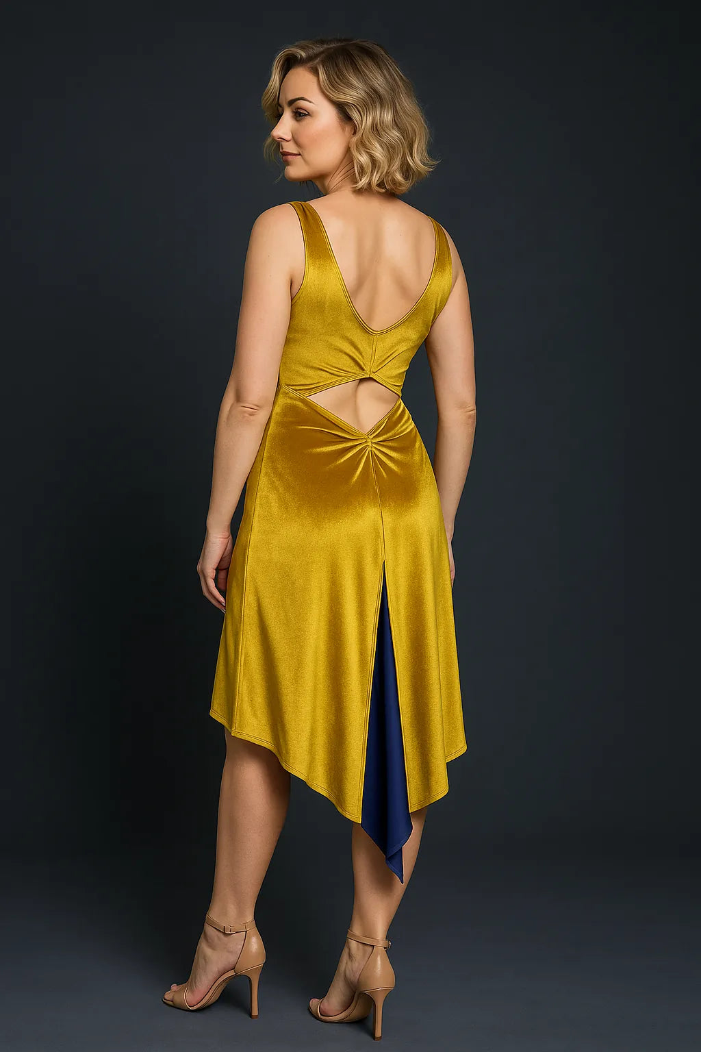 Woman wearing a golden velvet tango dress with cut-out design on a dark background, back view