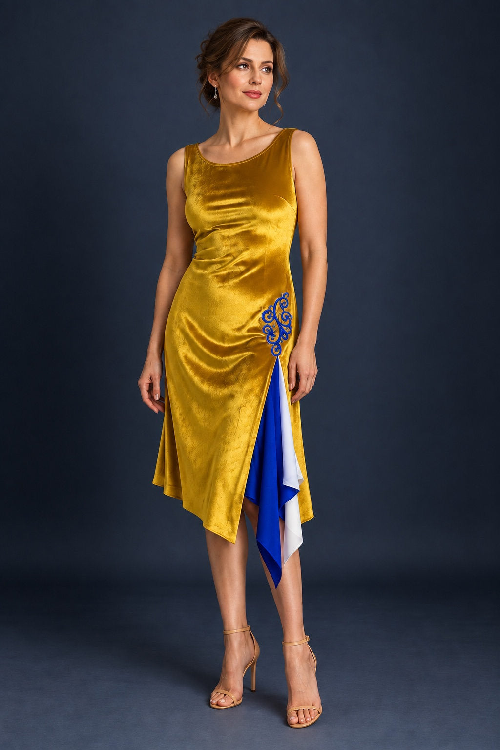 Gold velvet tango dress with blue embroidery, side slit and blue and white flowing panels, front view.