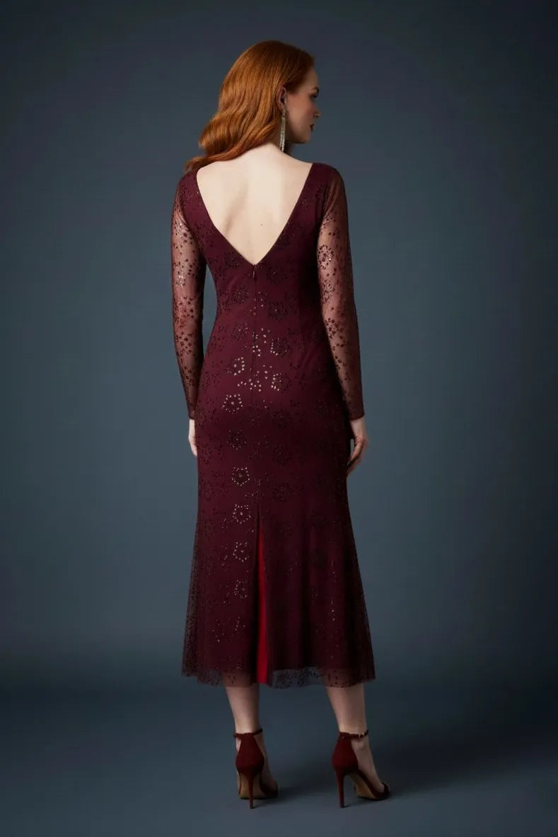 Woman wearing a deep bordeaux lace tango dress with long sleeves on a dark background, back view.