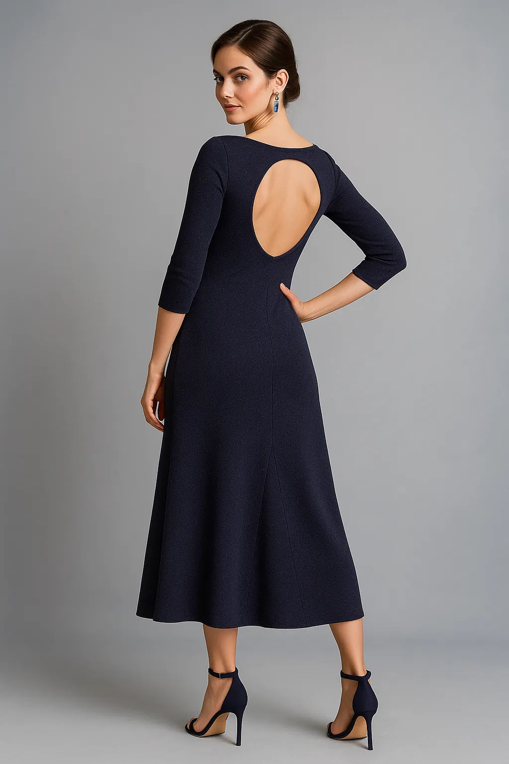 Woman wearing a shimmering dark violet tango dress with a cut-out back on a gray background