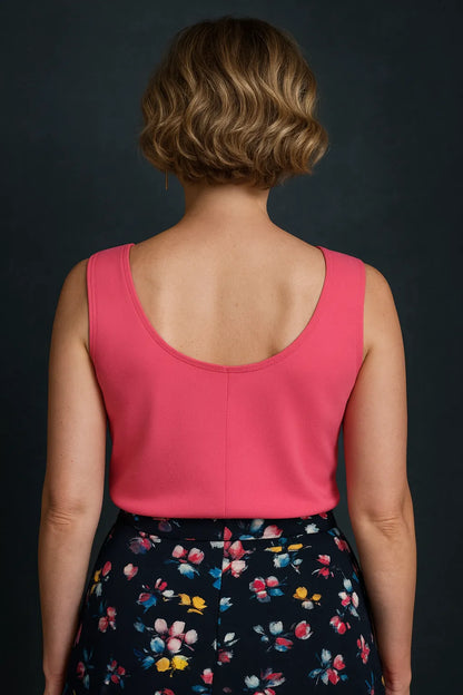 Woman wearing a pink tango top and floral skirt against a dark background, back view