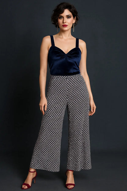 Woman wearing a navy tango top and patterned tango pants against a black background