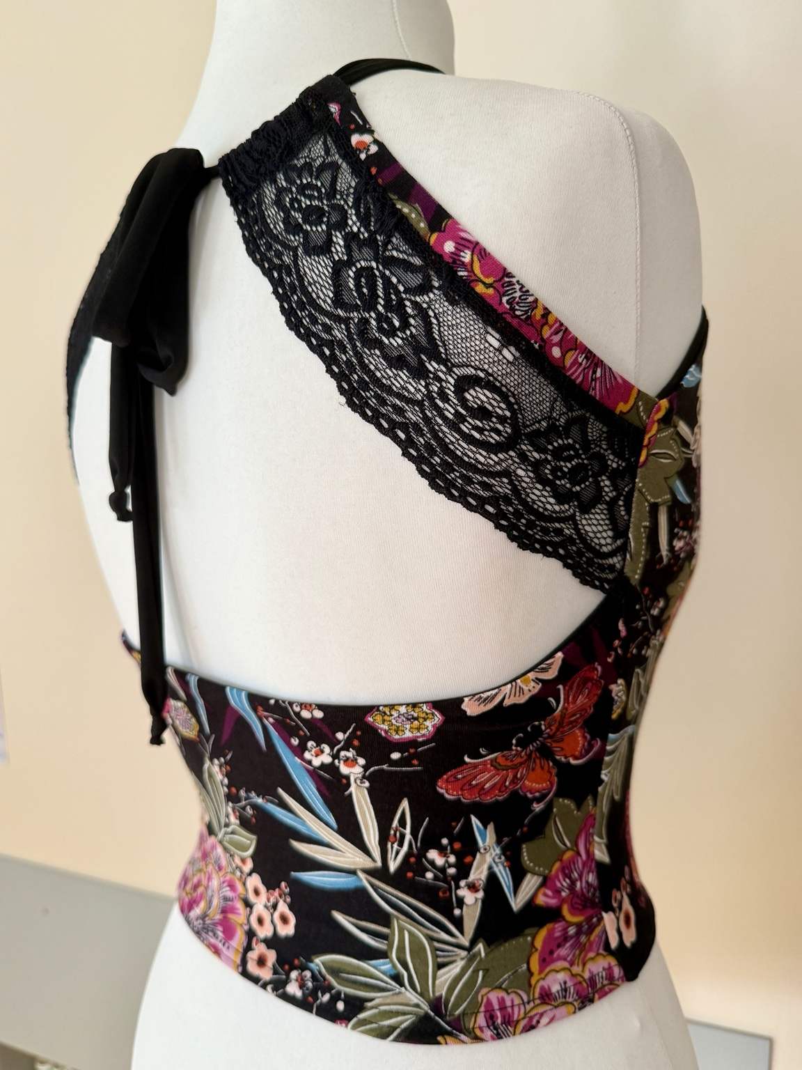 Back view of women’s tango top with an open lace back, adjustable ties, wide shoulder straps, and fitted jersey waist.